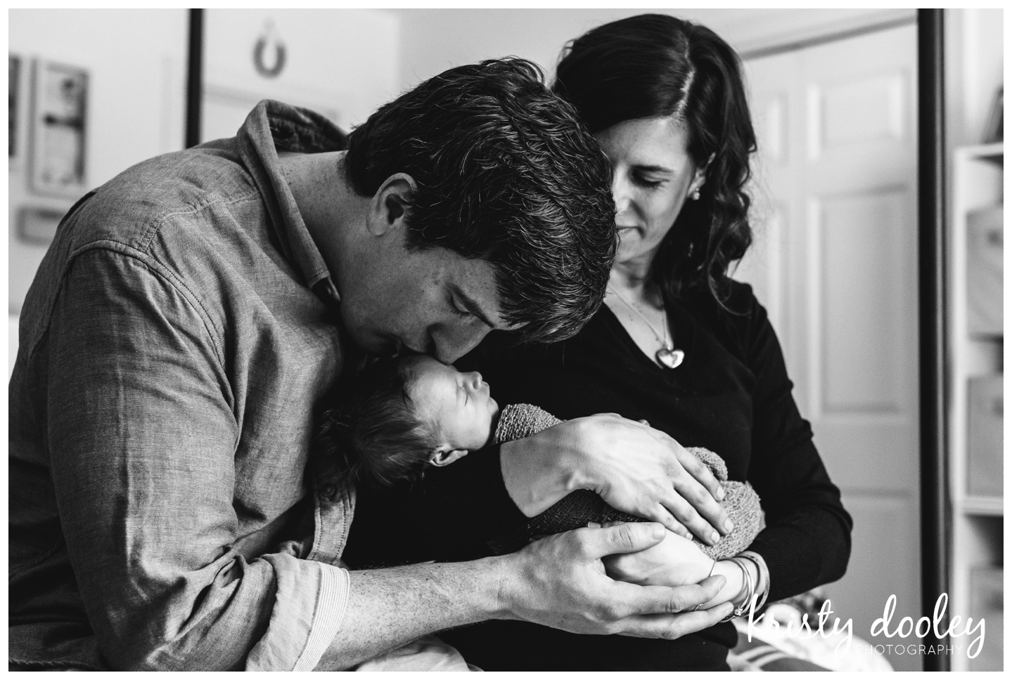 father kissing newborn baby black and white